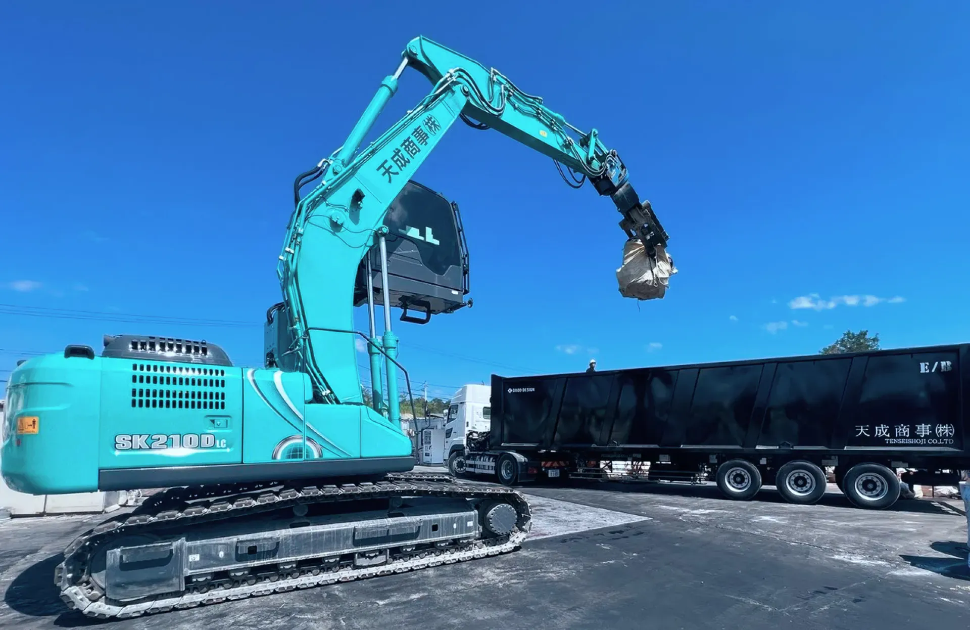 天成商事のショベルカーがスクラップ資源を処理している作業風景