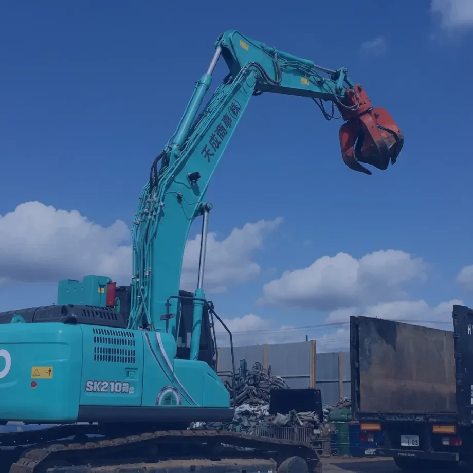 天成商事のショベルカーがスクラップ資源を処理している作業風景